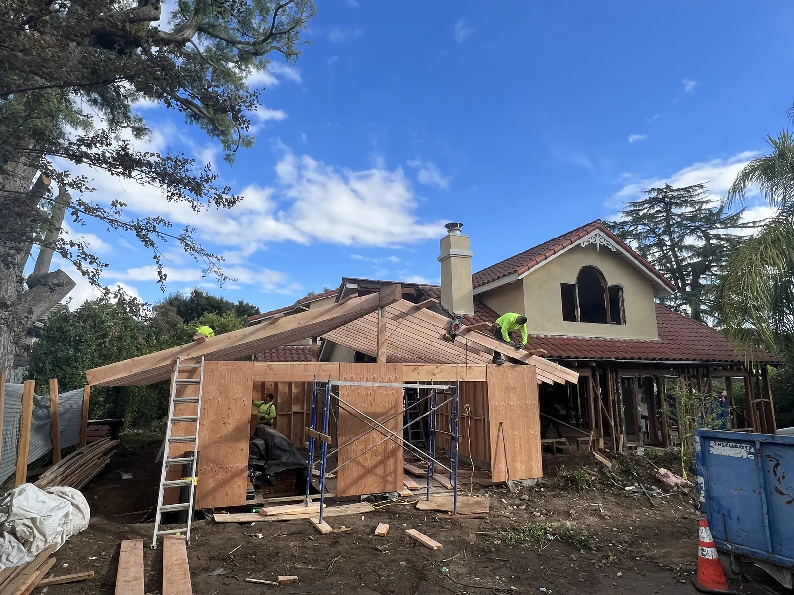 Crew members framing the new entry roof structure on scaffolding at PMK Development's La Cañada Flintridge new build.