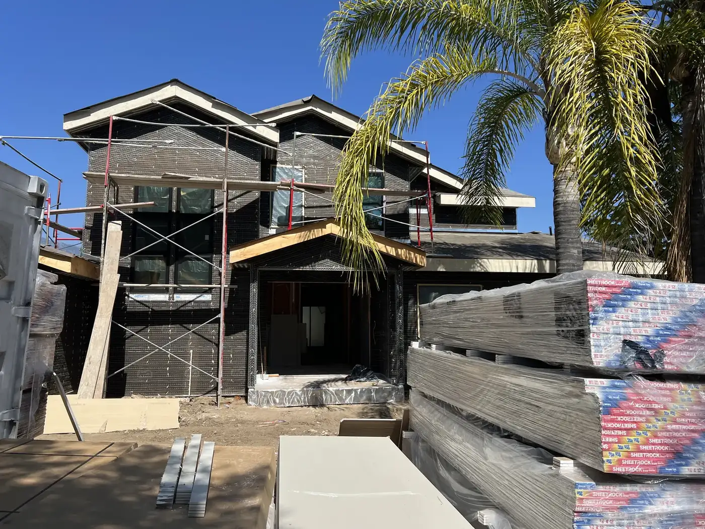 Weather barrier and stucco lath wrapping the exterior with drywall staged for delivery at PMK Development's La Cañada Flintridge new construction.