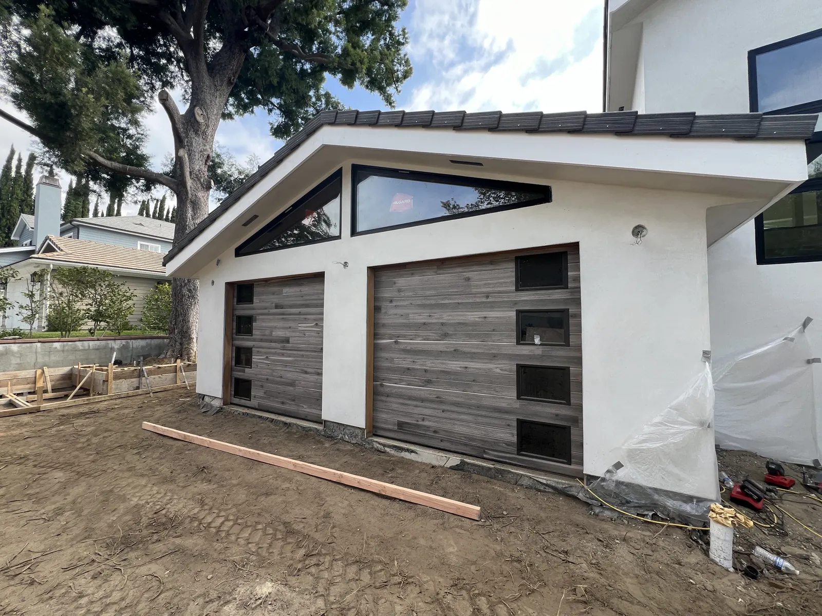 Wood-look garage doors and triangular gable glazing installed on the detached garage at PMK's La Cañada Flintridge new build.