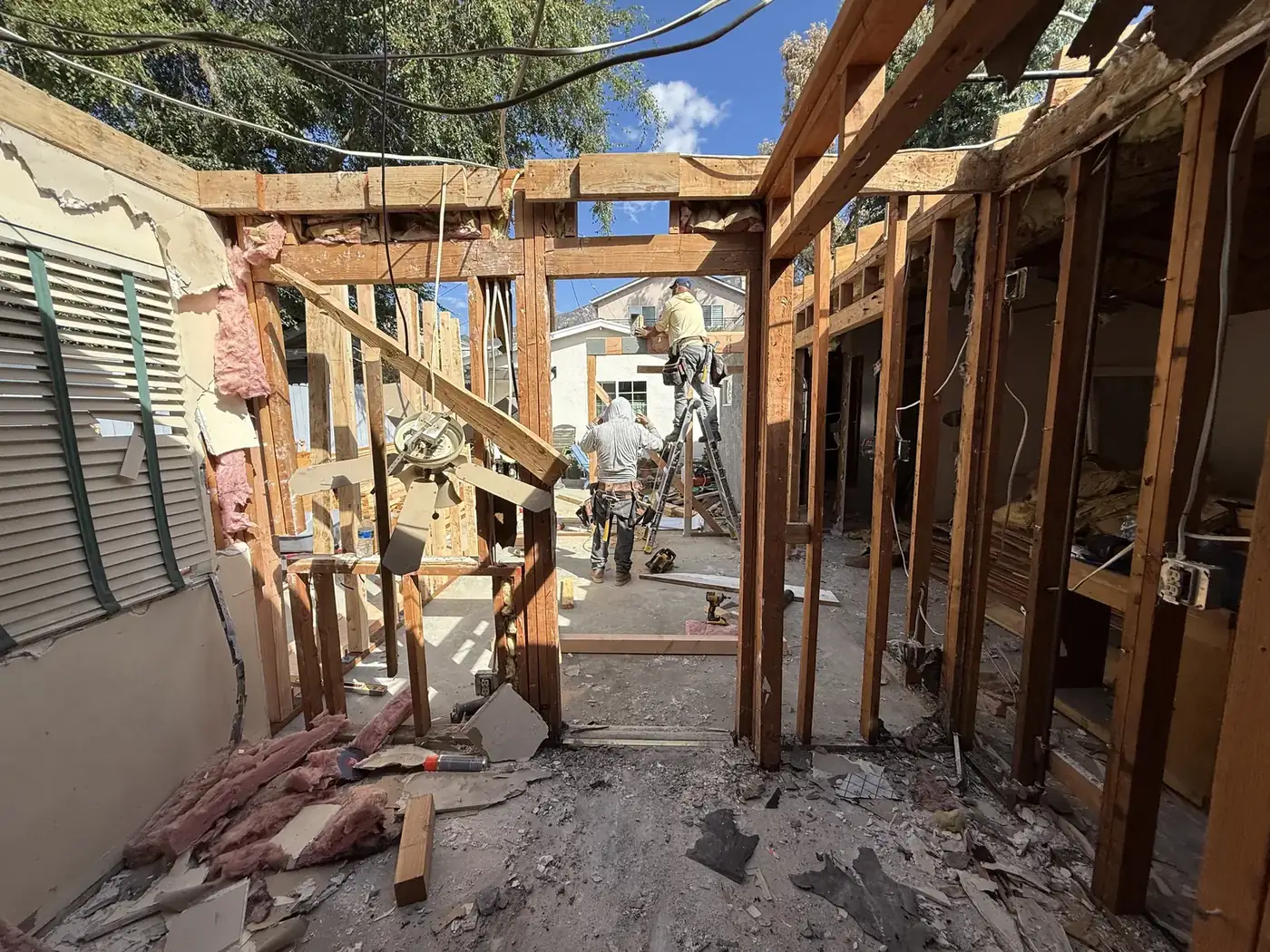 Crew members work atop ladders as the rear walls come down to connect the existing house to the new kitchen expansion at PMK's La Crescenta addition-and-remodel project.