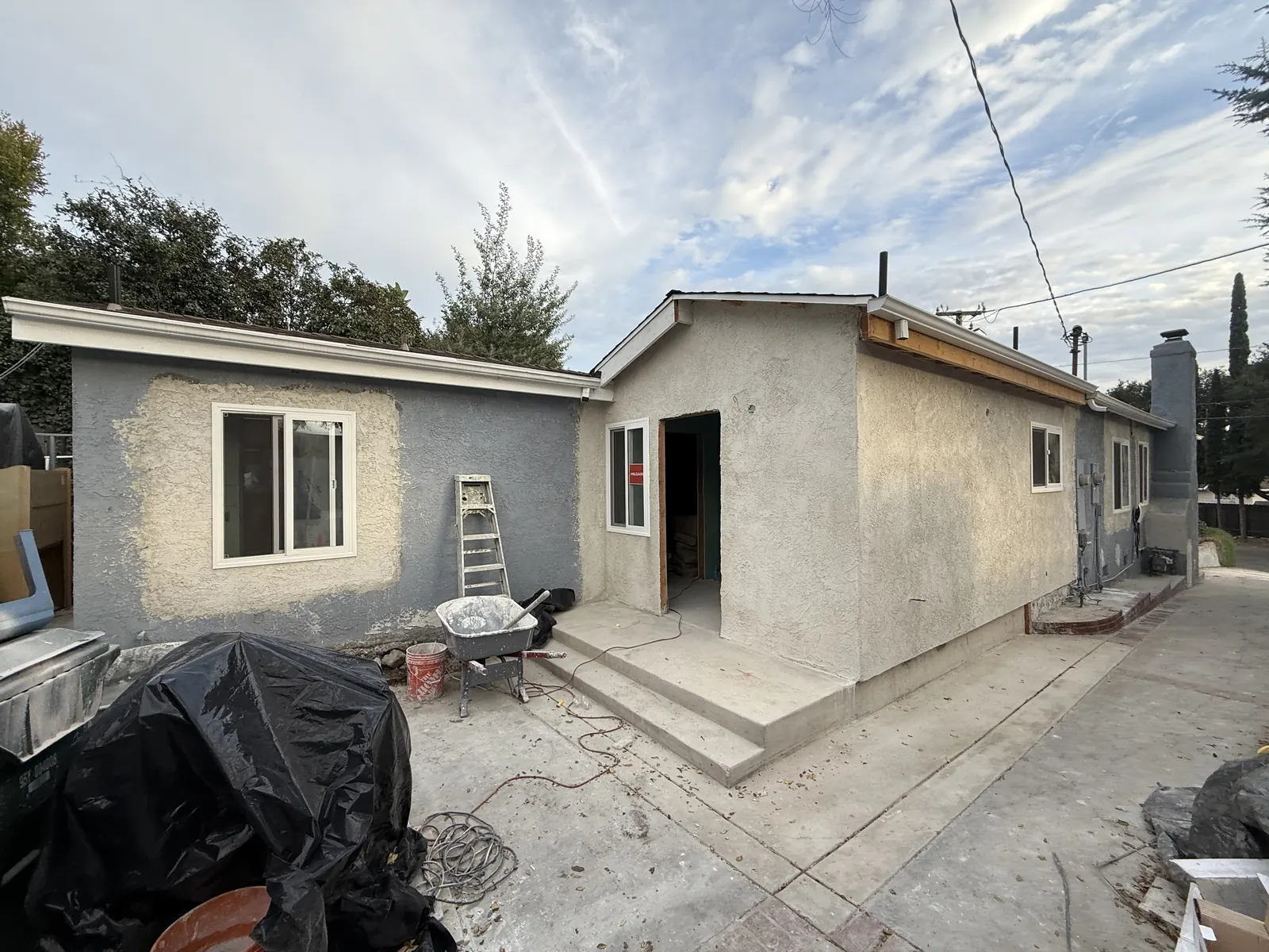 The rear addition wears its base stucco coat beside new concrete entry steps where it joins the existing house at PMK's La Crescenta addition-and-remodel project.