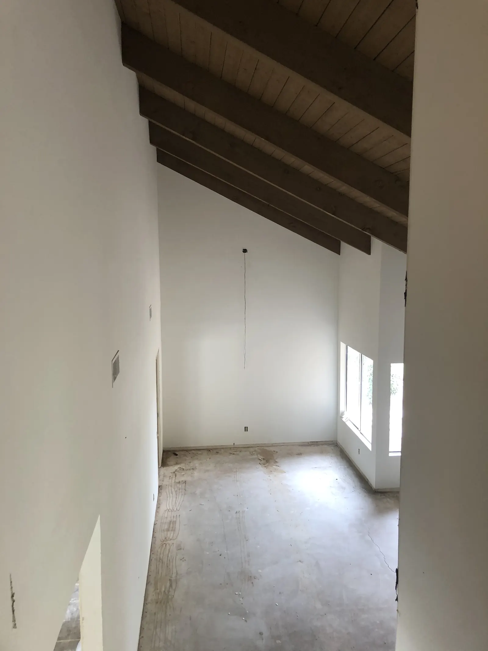 Living room with exposed wood beam ceiling, skylight, and freshly finished drywall during the PMK home remodel on Glenwood Avenue in Fullerton.