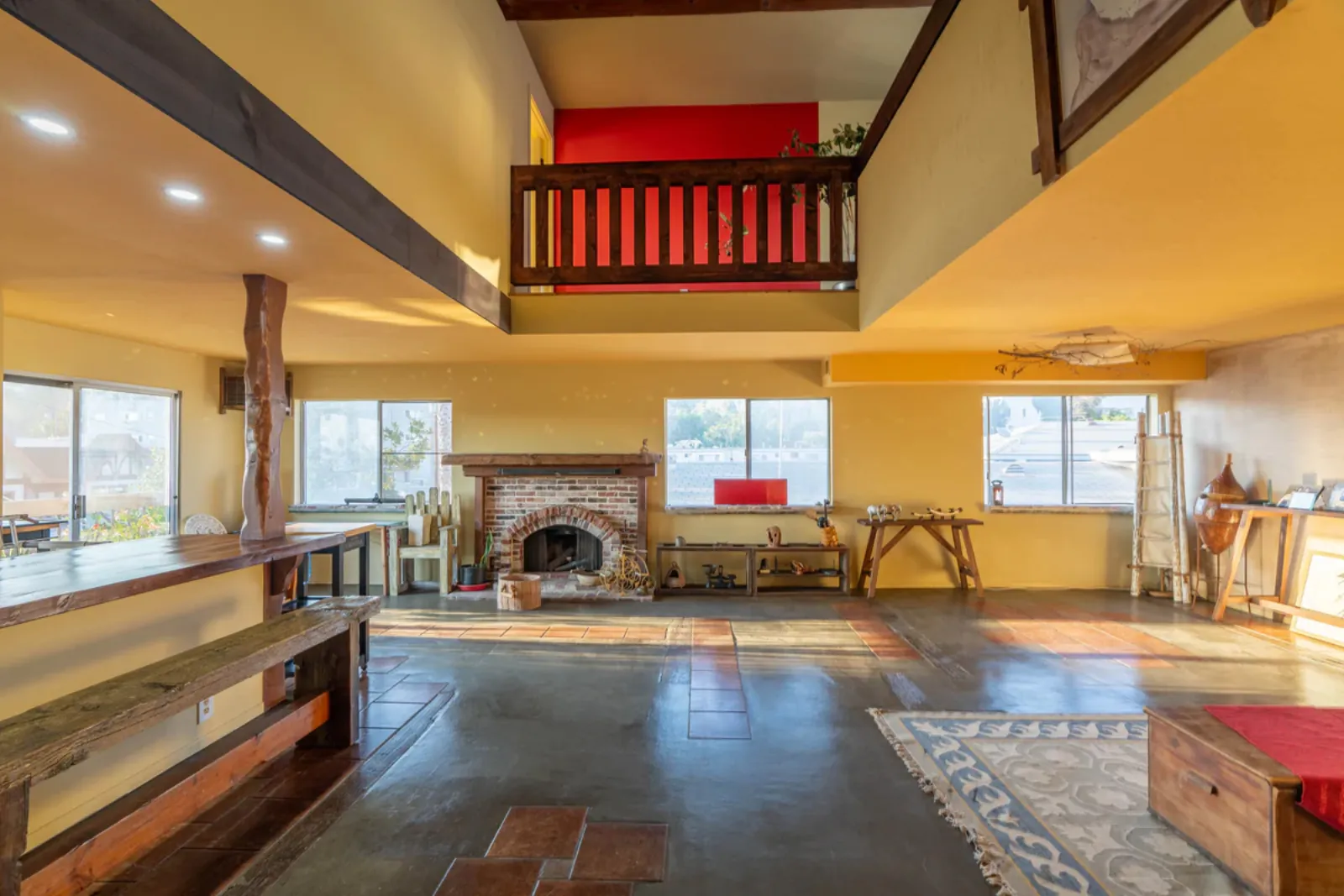 Living and dining area of the Harvard, Los Angeles whole-home remodel, with the original exposed wood beams, loft, and brick fireplace preserved and refinished