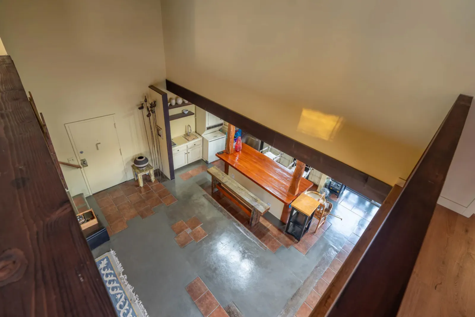 View down from the loft into the remodeled kitchen and dining area of a 1960s Los Angeles home, showing the updated bar seating and refinished flooring