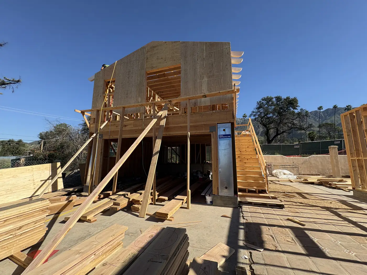 Sheathed second-story volume rising above braced framing at the Las Flores Drive rebuild in Altadena.
