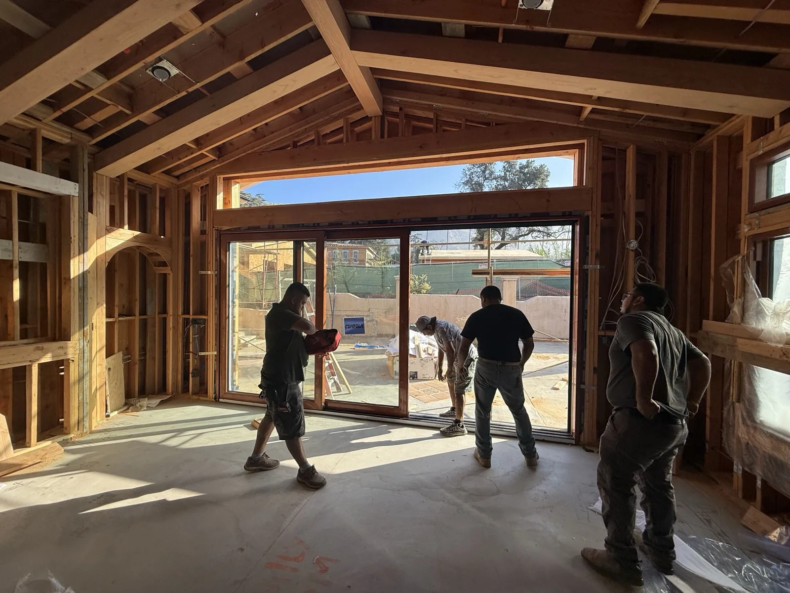 Crew guiding a large multi-panel sliding glass door into its opening in the vaulted great room.