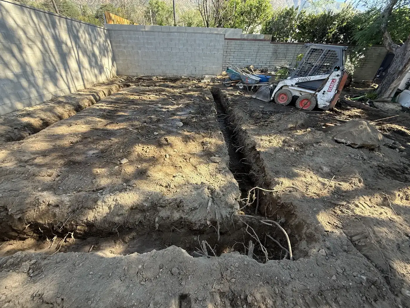 Footing trenches dug across the compacted pad with a skid steer on site in Altadena.