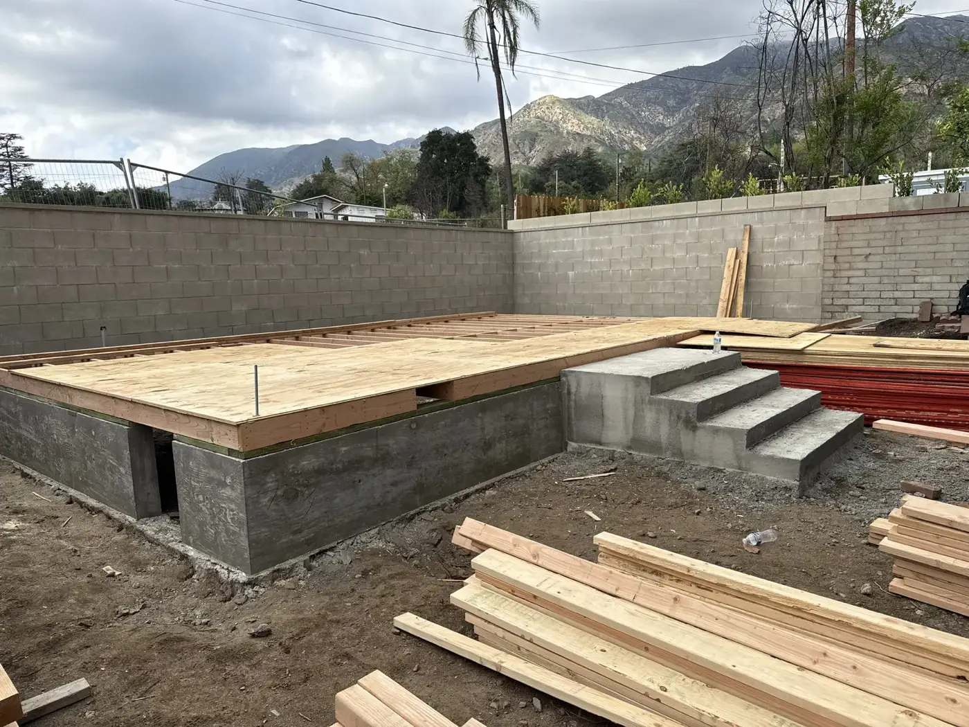 Poured block stem walls and decked subfloor with framing lumber staged on site in Altadena.
