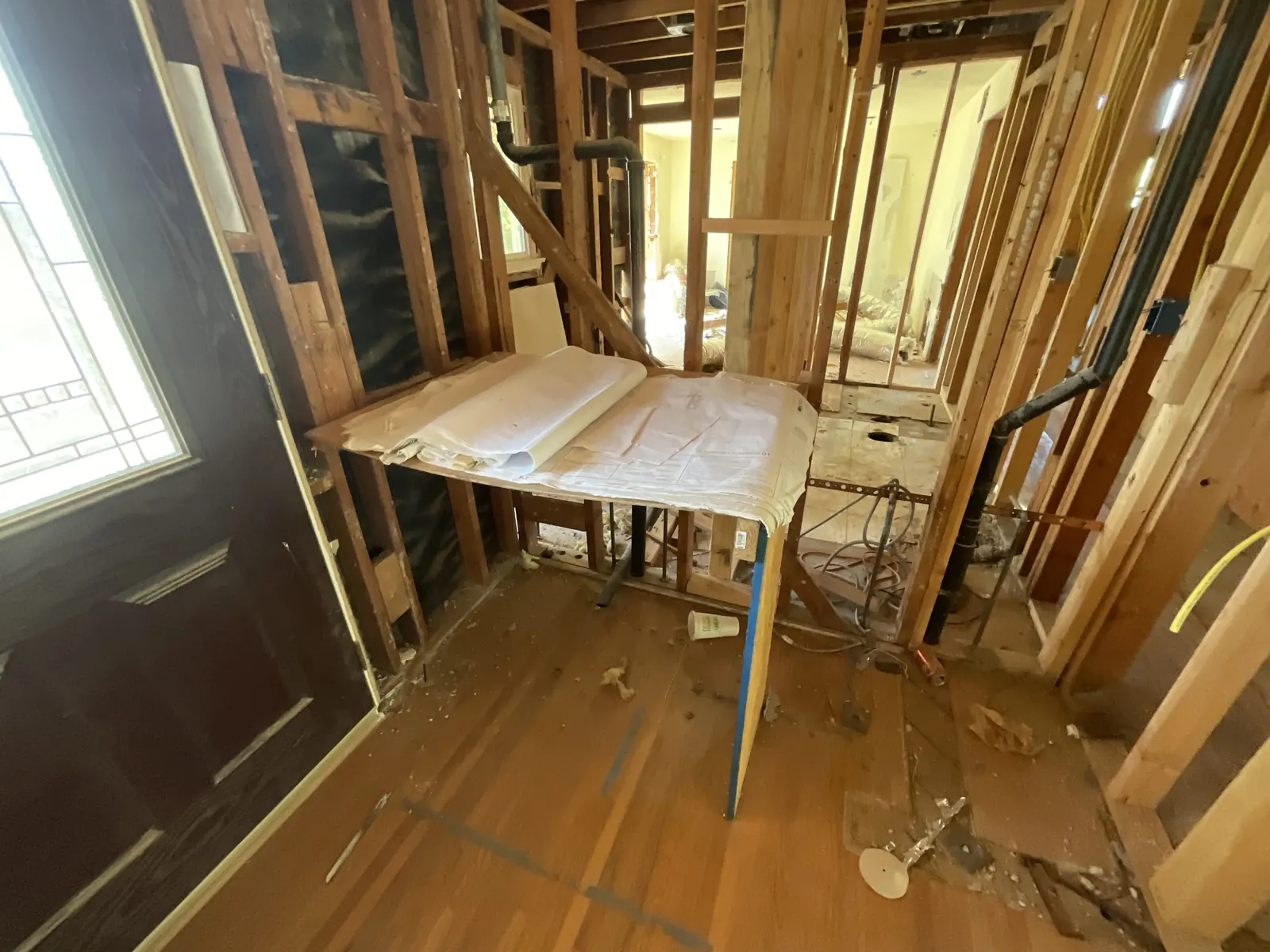 Interior hallway gutted to bare wall studs and exposed plumbing lines during selective demolition at PMK's addition-and-renovation project in La Cañada Flintridge.