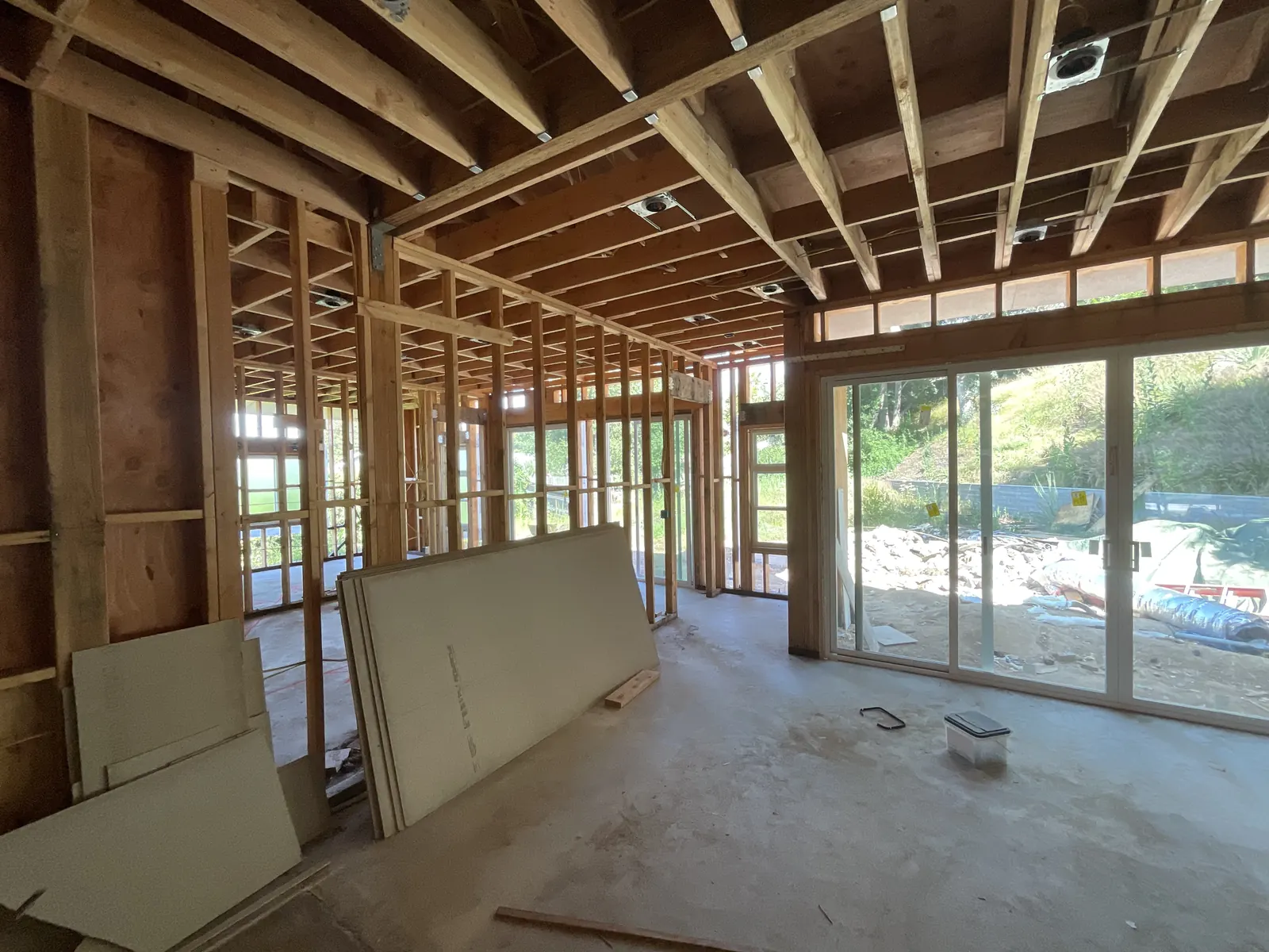 Interior view of new ceiling joists, clerestory framing, and freshly installed glass sliders filling the main living space with light at PMK's addition-and-renovation project in La Cañada Flintridge.