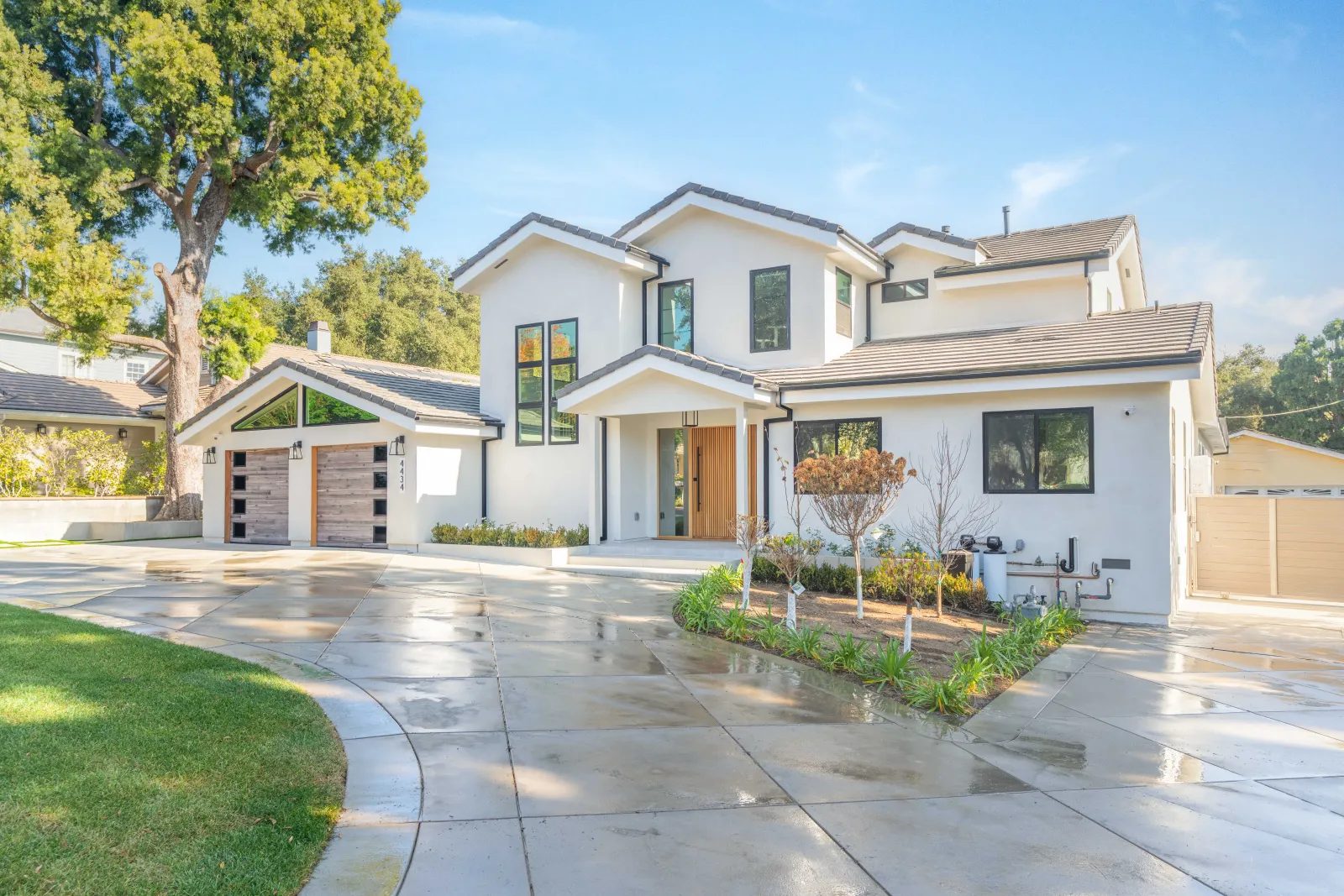 Finished two-story white stucco home with a wood front door and curved concrete driveway, built by PMK Development.